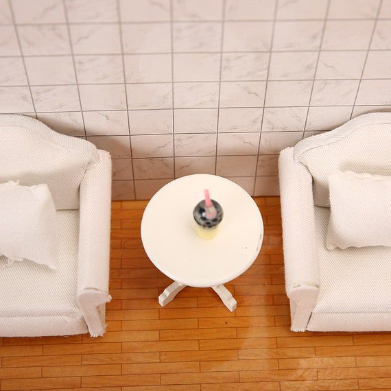 Two white chairs and a table on a wooden floor.