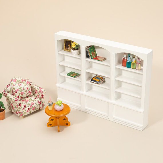 A doll house with bookshelves and a chair.